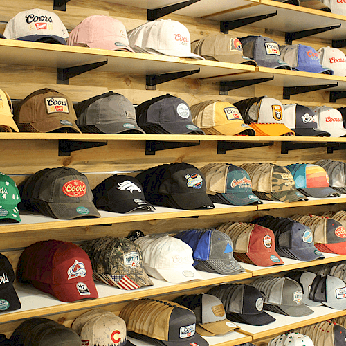 The image shows shelves filled with various baseball caps in different colors and designs, arranged neatly in a store or display area.