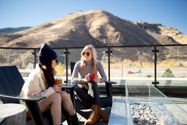 two women sitting on a patio with a mountain view