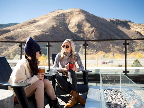 two women sitting on a patio with a mountain view