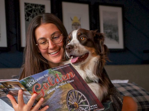 A person with glasses reads "Welcome to Golden" while holding a dog. A red mug labeled "The Eddy" is in the foreground.