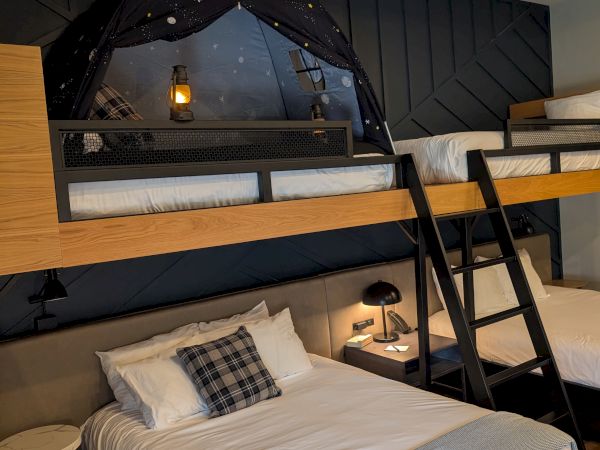 A cozy loft bedroom with a starry black canopy tent over the bed and glowing lanterns, making a dreamy hideaway.