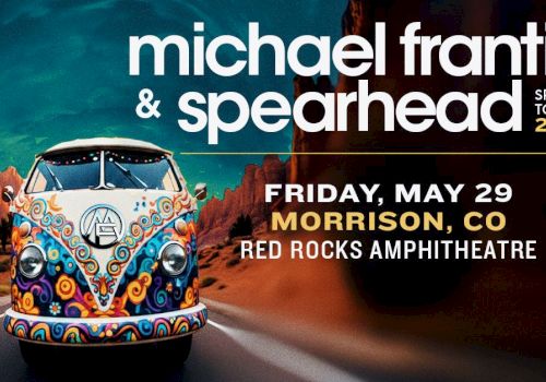 A colorful vintage VW bus drives on a desert road toward a concert poster for Michael Franti & Spearhead, showing date and location.