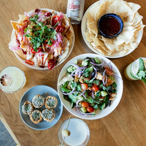 A table of tacos, chips with salsa, salad, a beer can, and drinks&mdash;an appetizing spread ready to eat.