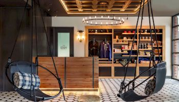 A cozy room with hanging chairs, a wooden counter, modern decor, and shelves stocked with apparel and other items.